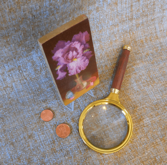 Small format oil painting of a still life with an iris in a translucent glass vial