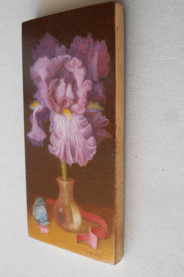 Small format oil painting of a still life with an iris in a translucent glass vial