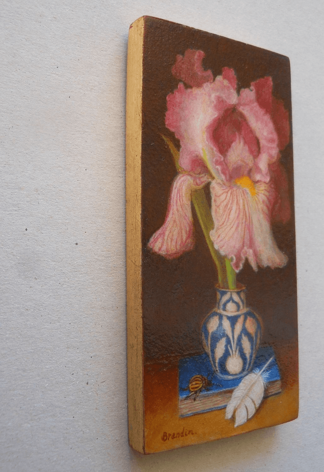 Still life with pink iris, blue book and white feather