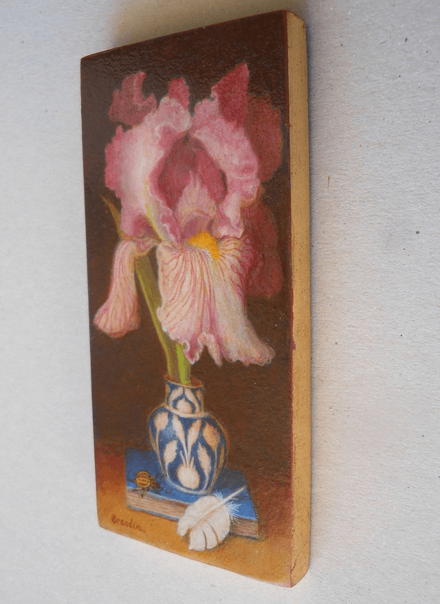 Still life with pink iris, blue book and white feather
