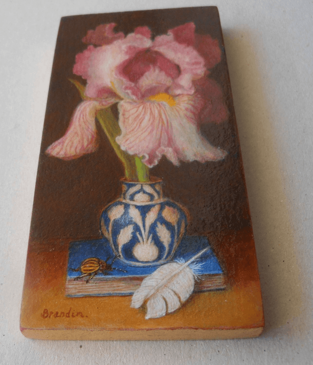 Still life with pink iris, blue book and white feather